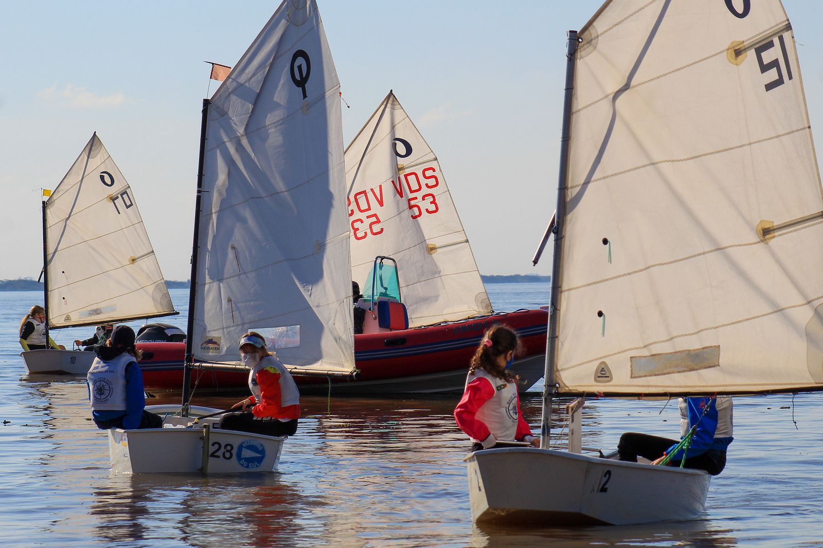 Criança velejando em barco Optimist durante aula