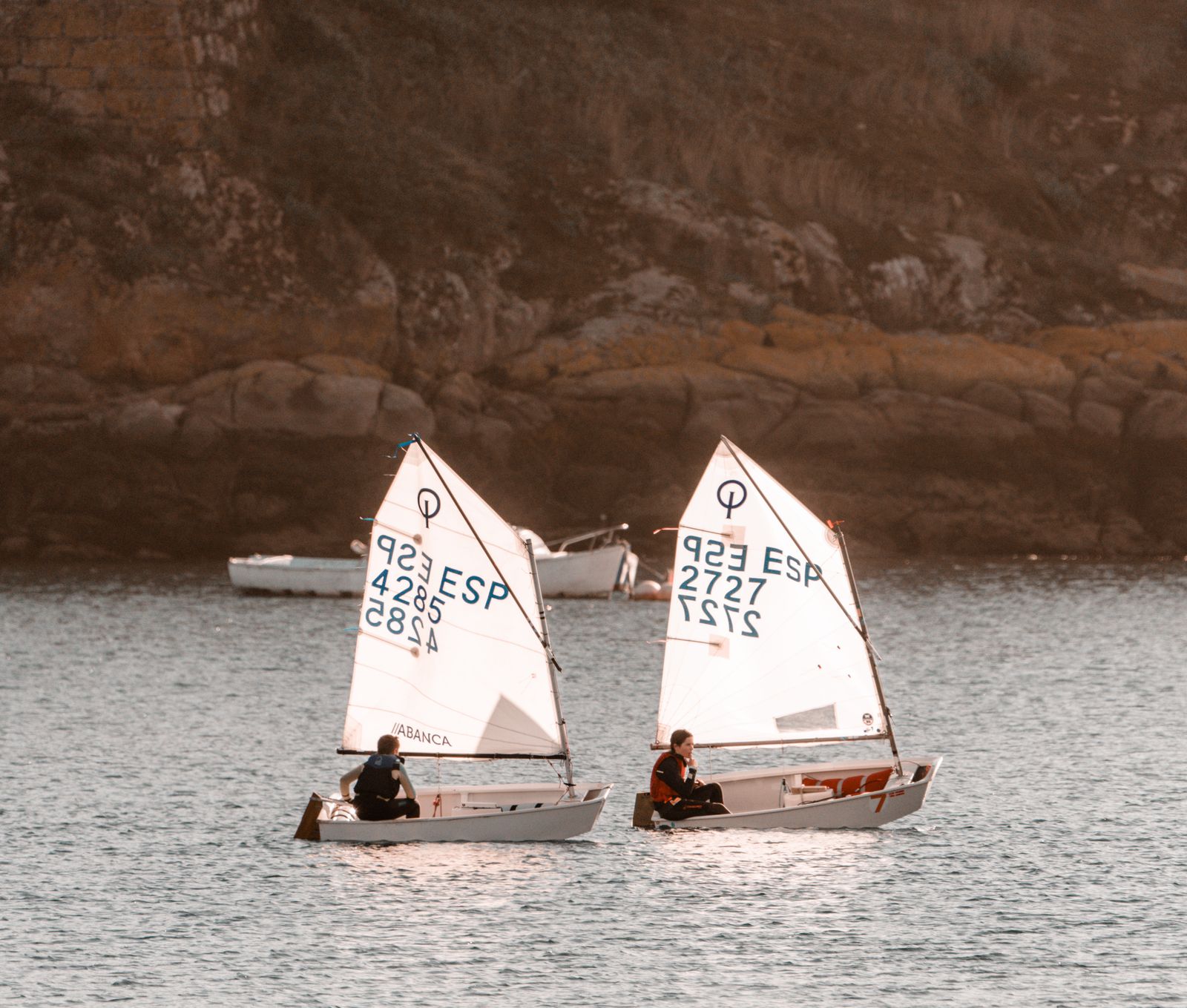 Duas crianças velejando juntas em barcos Optimist